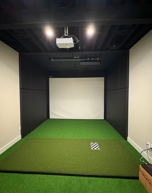 Empty indoor golf simulator room with turf.