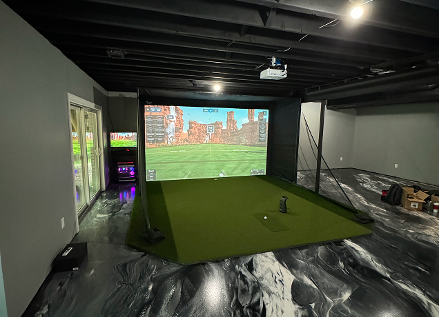 Basement golf simulator setup with green turf.