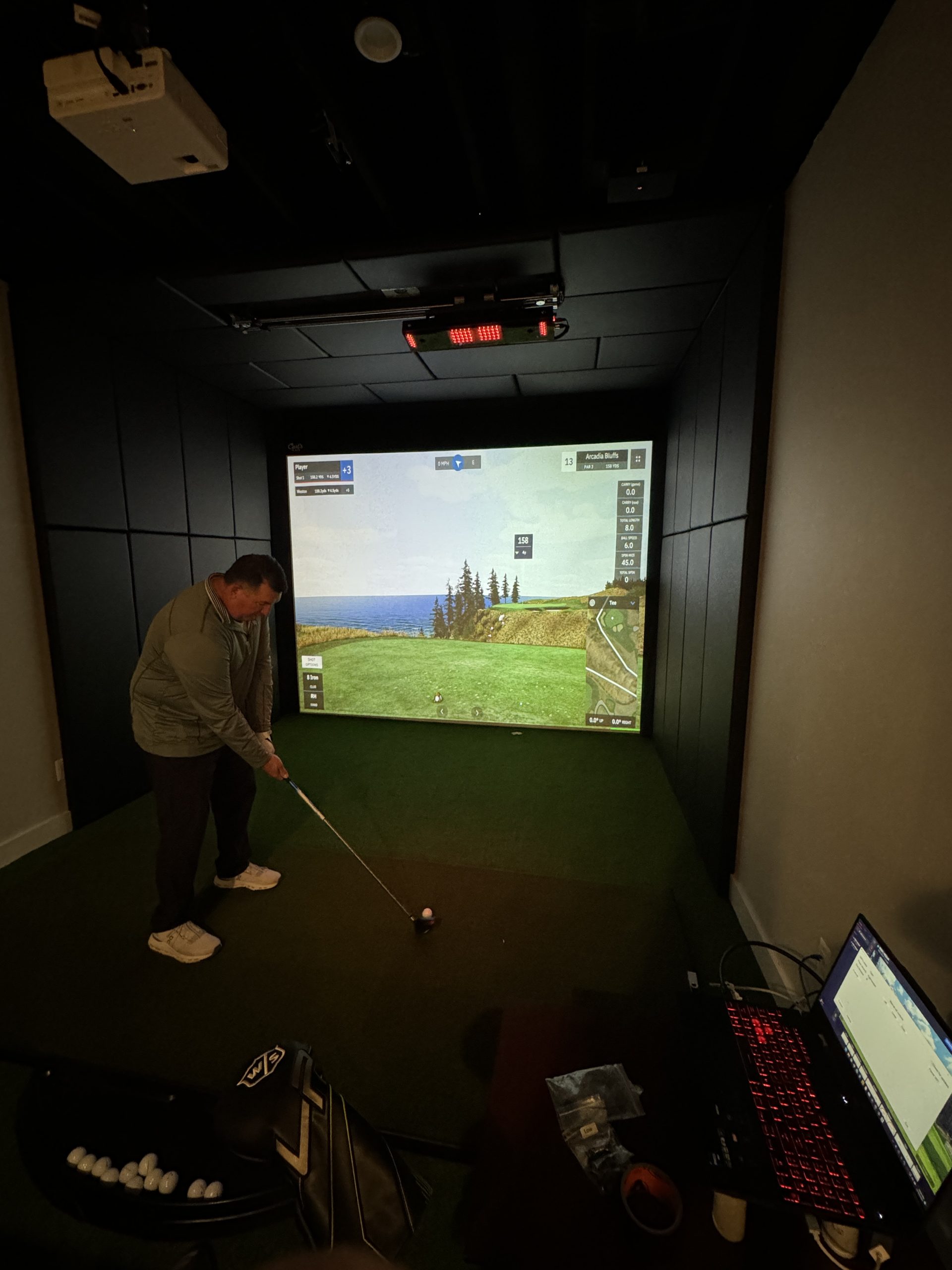 Man swinging a golf club on simulator.
