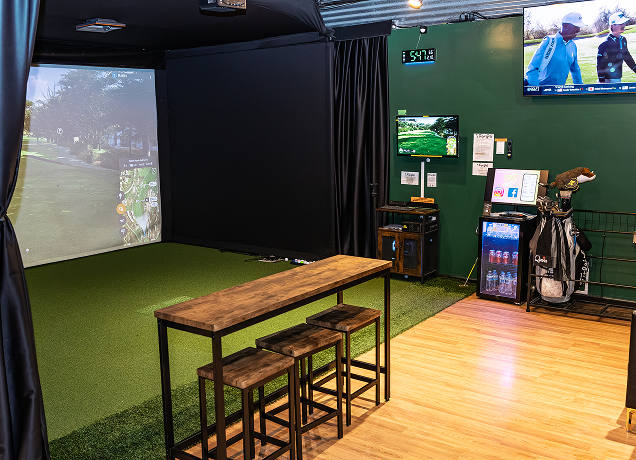Indoor golf simulator with a high bar table.