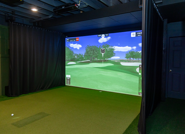 Indoor golf simulator with black side curtains.